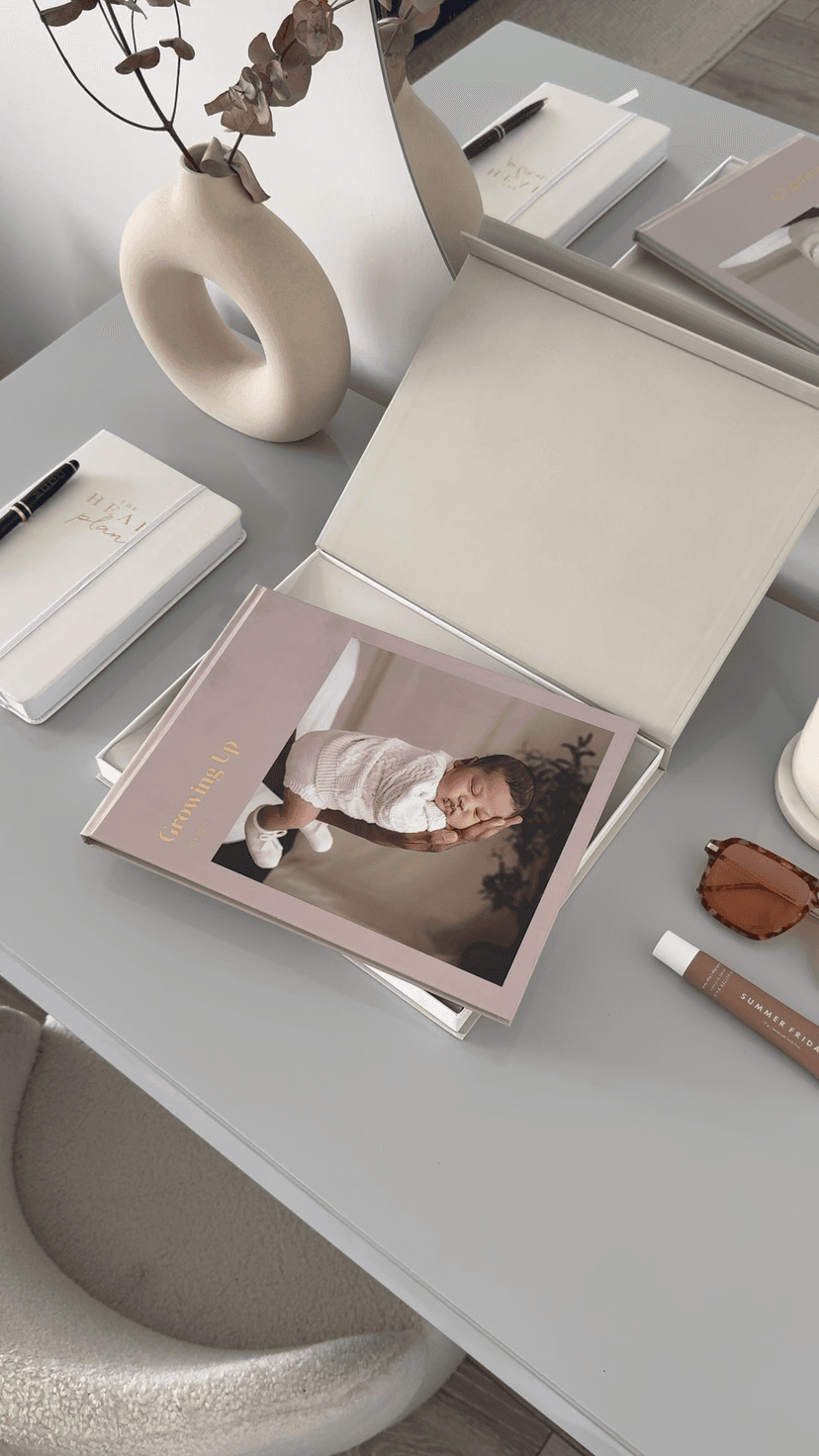 A desk with a photo book featuring a newborn baby on the pastel pink cover