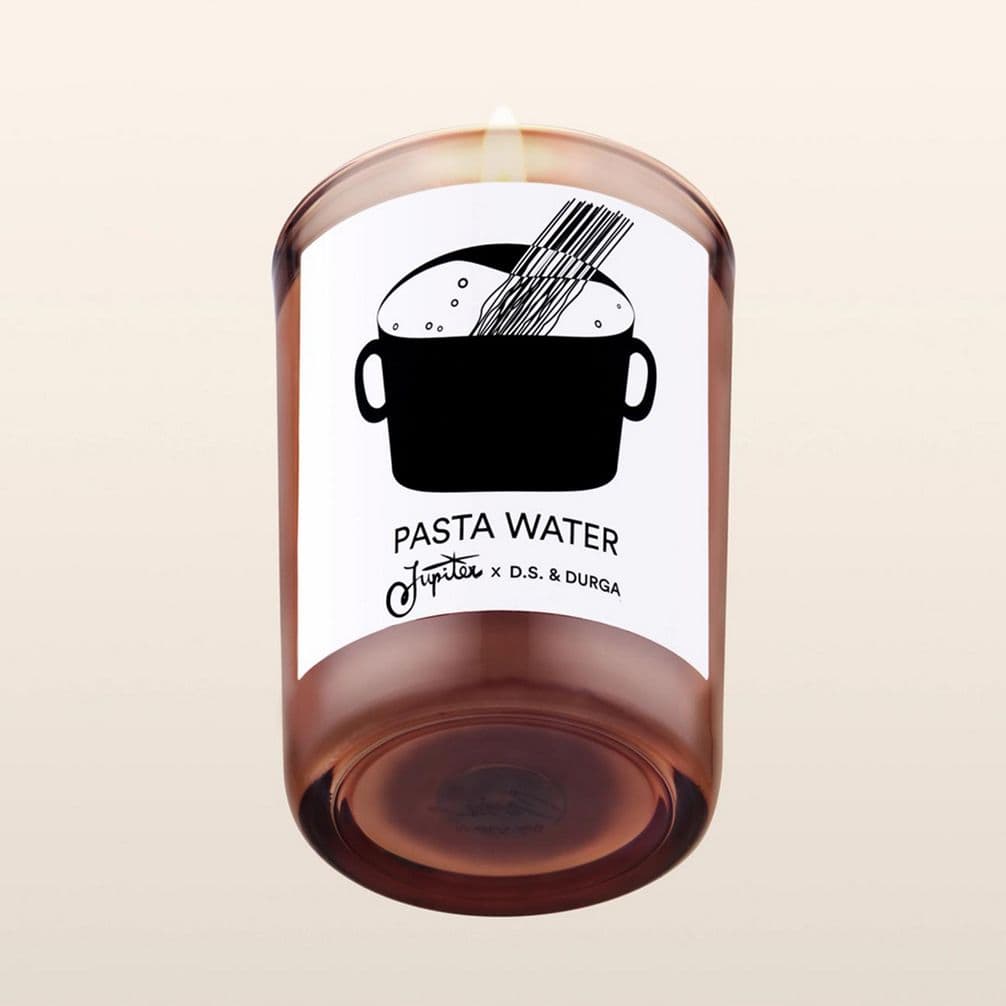Brown candle with label showing a pot of boiling pasta and text "PASTA WATER." The label features logos for a collaboration.