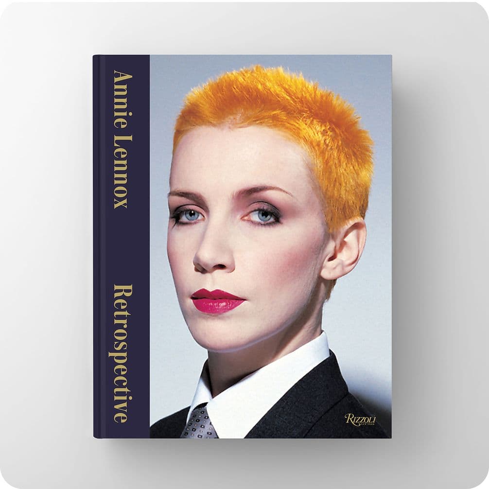 Book cover titled "Annie Lennox: Retrospective" featuring a person with short orange hair, red lipstick, and a suit. Published by Rizzoli.