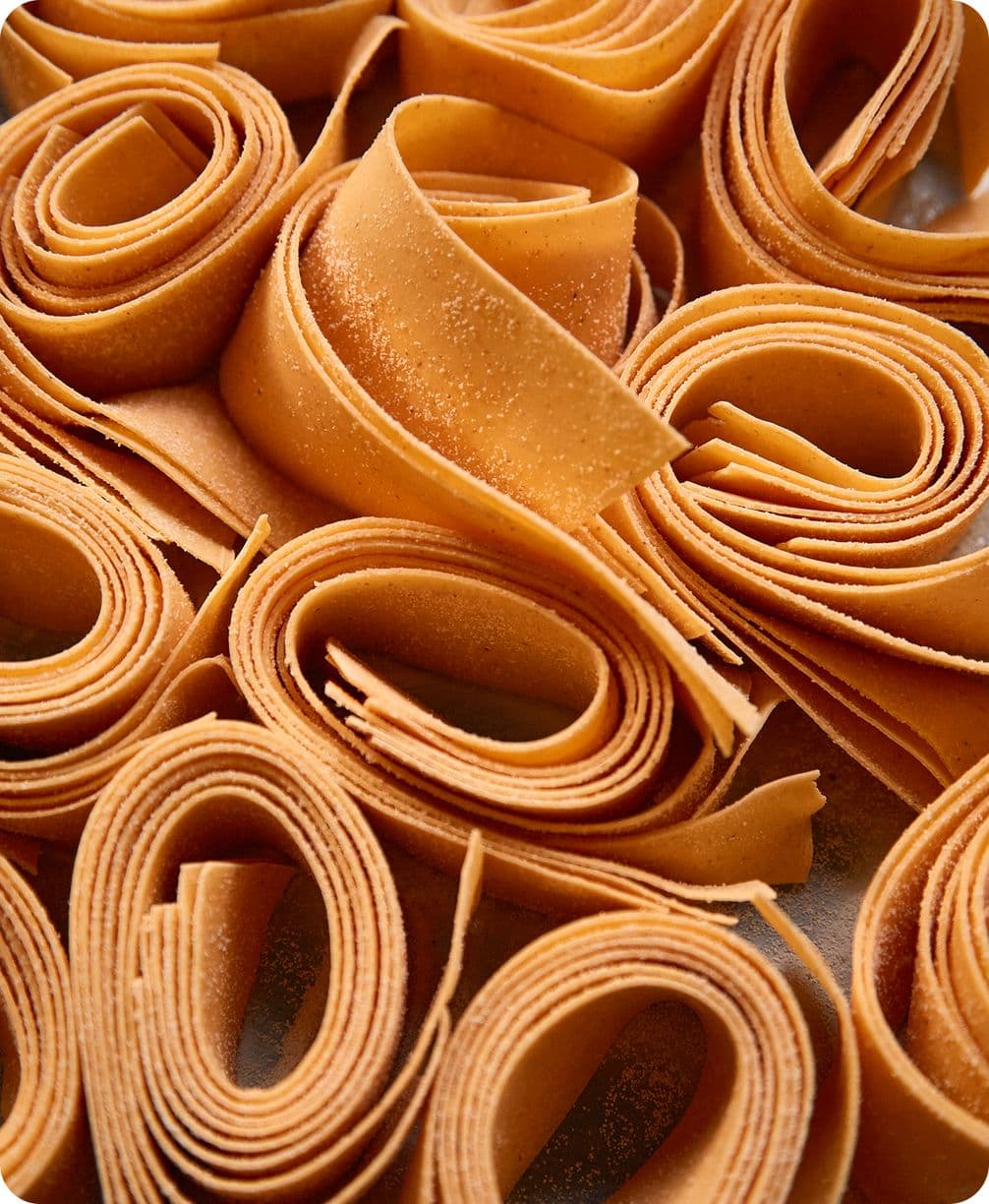 Close-up of tightly rolled thin caramel-colored strips forming spiral nests, textured with fine granules