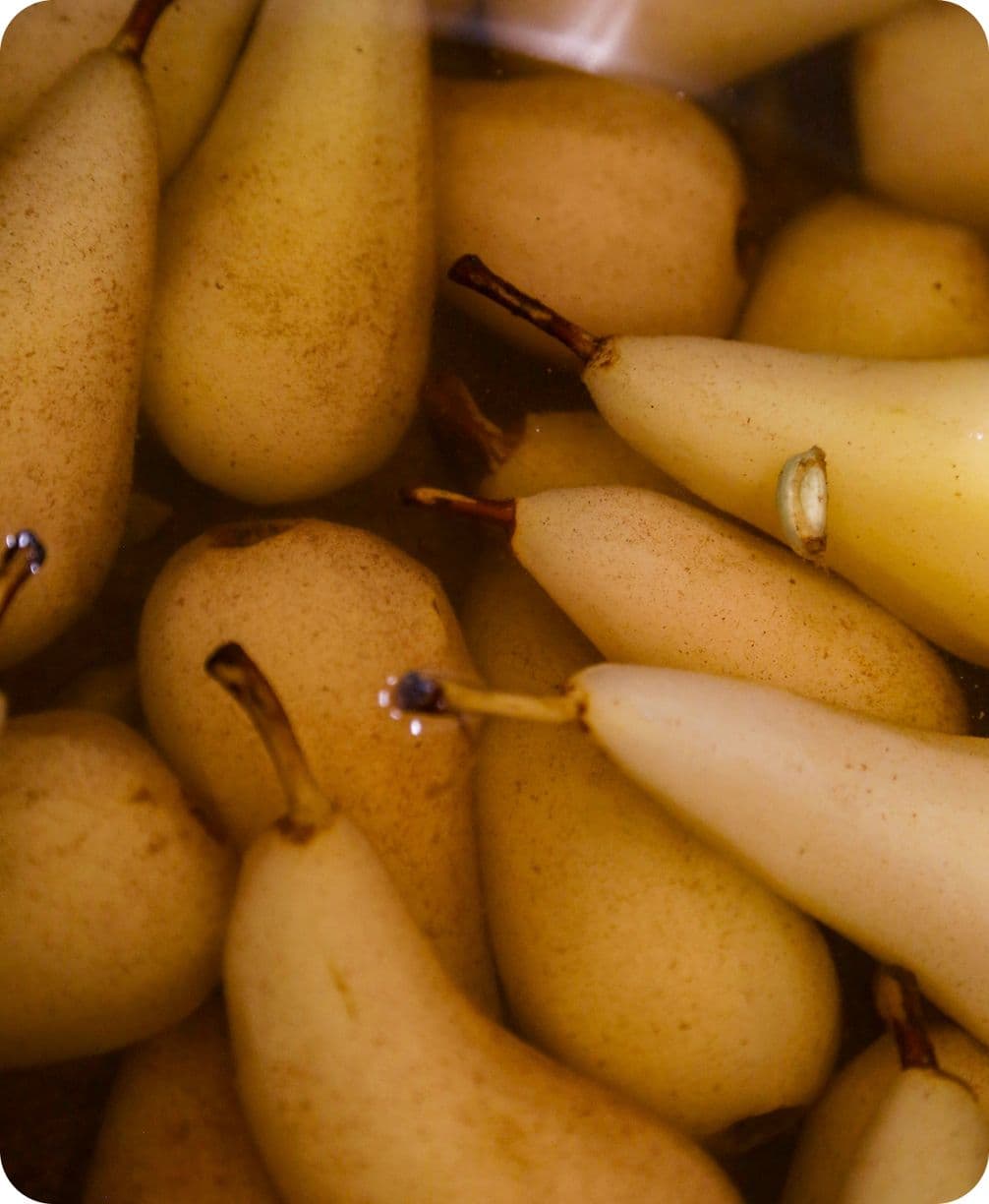 Close-up of clustered yellow pears with stems, bathed in warm light and subtle reflections.