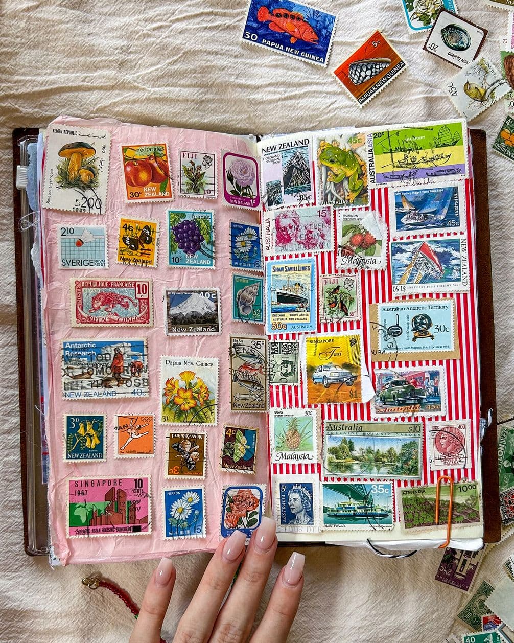 Open album of colorful vintage postage stamps from around the world, a hand holding the page.