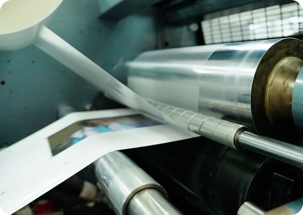 Close-up of a printing press in operation, with paper passing through rollers and an image being printed.