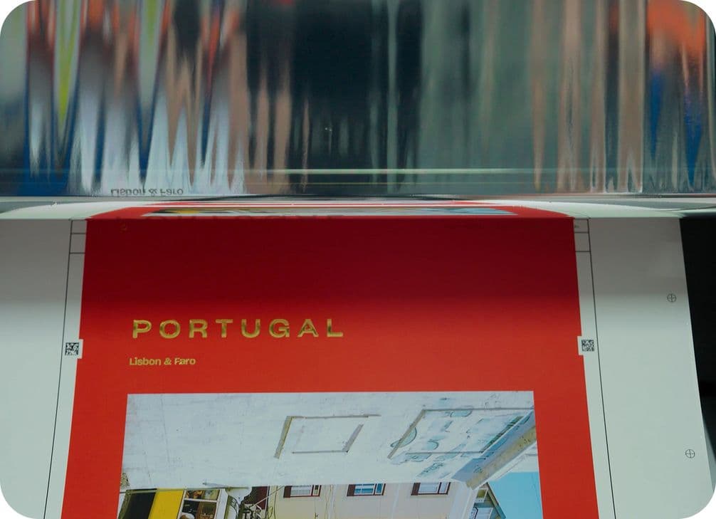 A printing sheet with "PORTUGAL" in gold text on a red background, partially reflected in a shiny surface above.