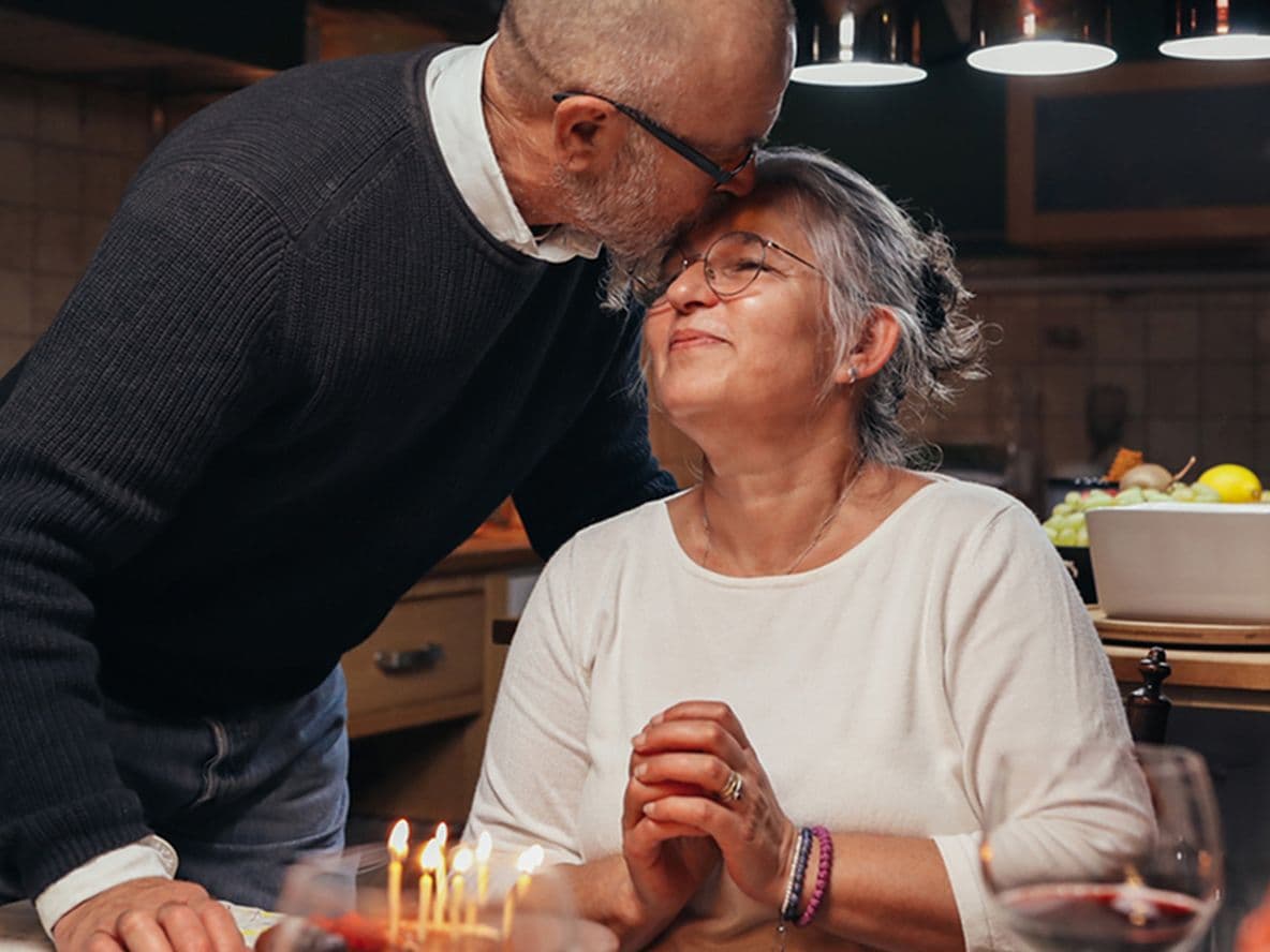 A husband kissing his wife on the forehead during a celebratory dinner