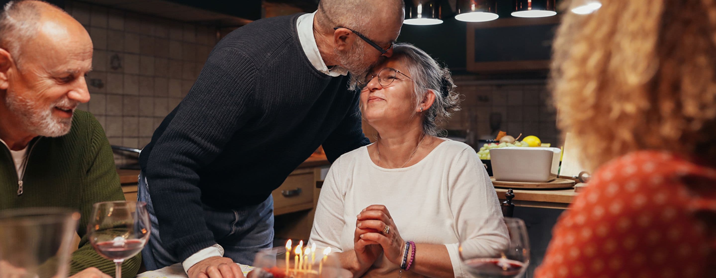 A husband kissing his wife on the forehead during a celebratory dinner