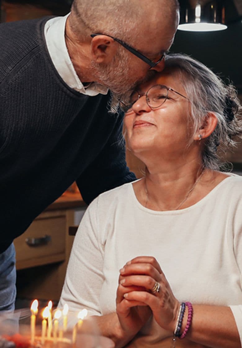 A husband kissing his wife on the forehead during a celebratory dinner
