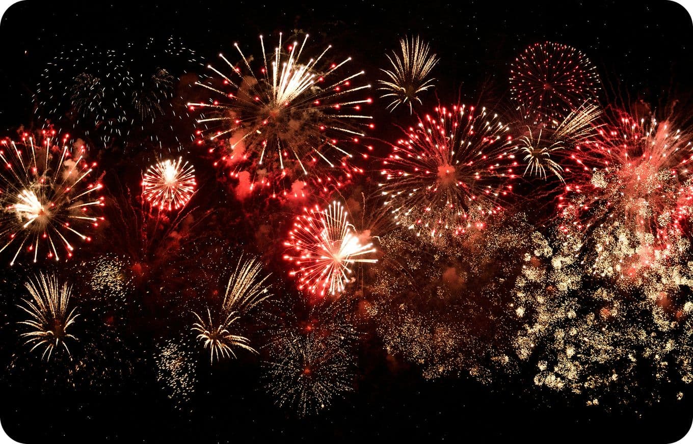 A vibrant display of red and gold fireworks bursting against a dark night sky.