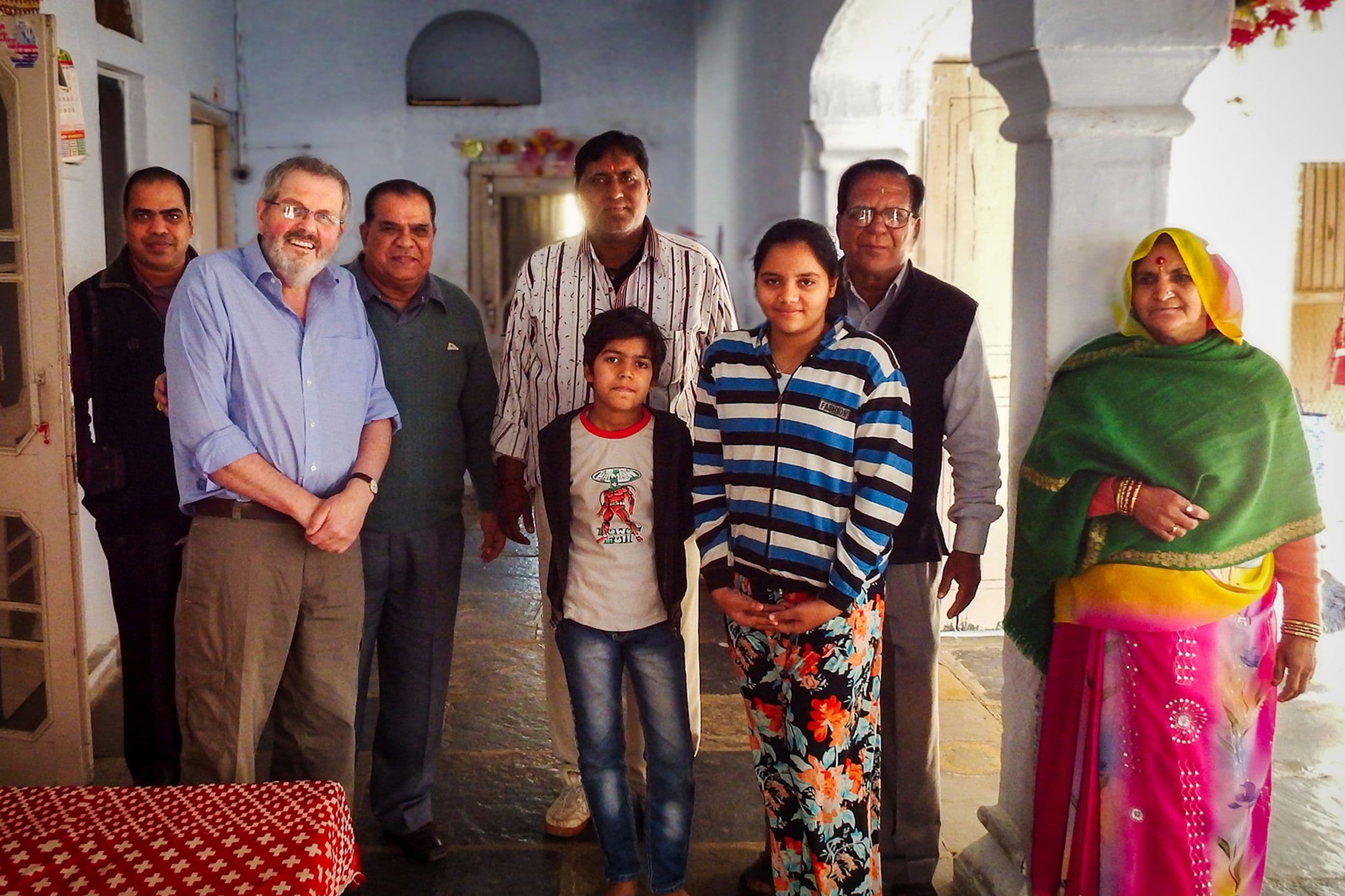 Geoffrey standing with Radheshyam and Satynarain Joshi and family in their house in Bhilwara