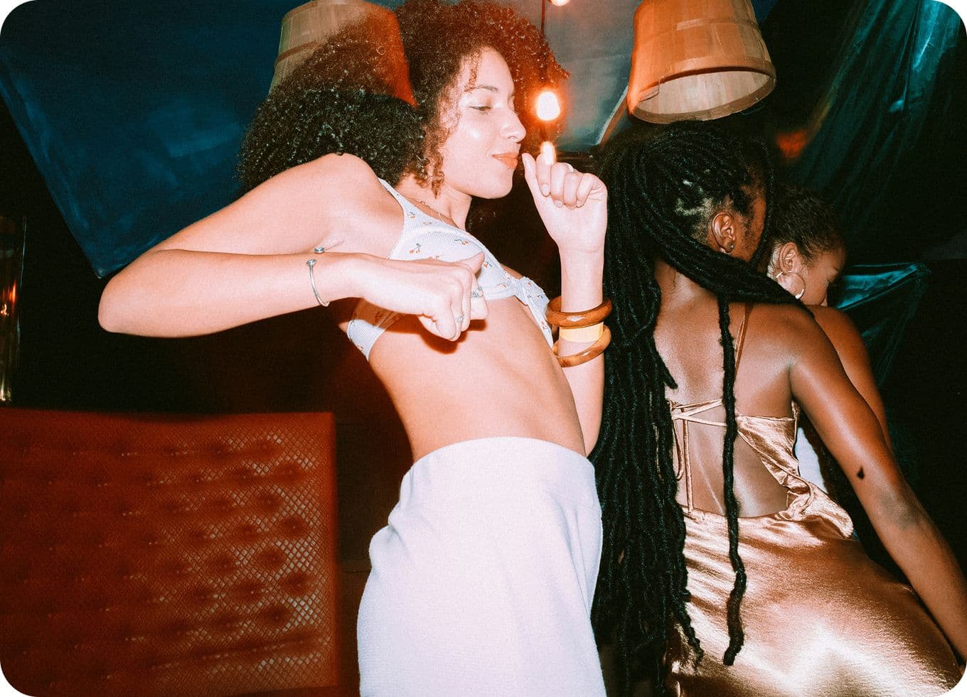 Two people dancing energetically in a dimly lit room, with vibrant lighting and colorful decor.