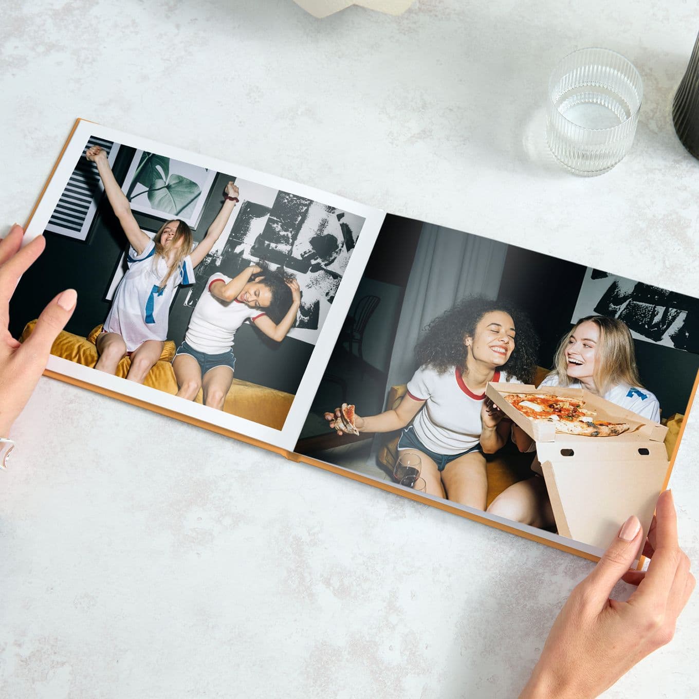 Hands holding a yellow Popsa Photo Book featuring images of teenage friends dancing and eating pizza