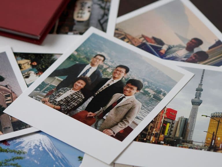 A collection of scattered photographs, including a group portrait and scenic views of a city skyline and a mountain.