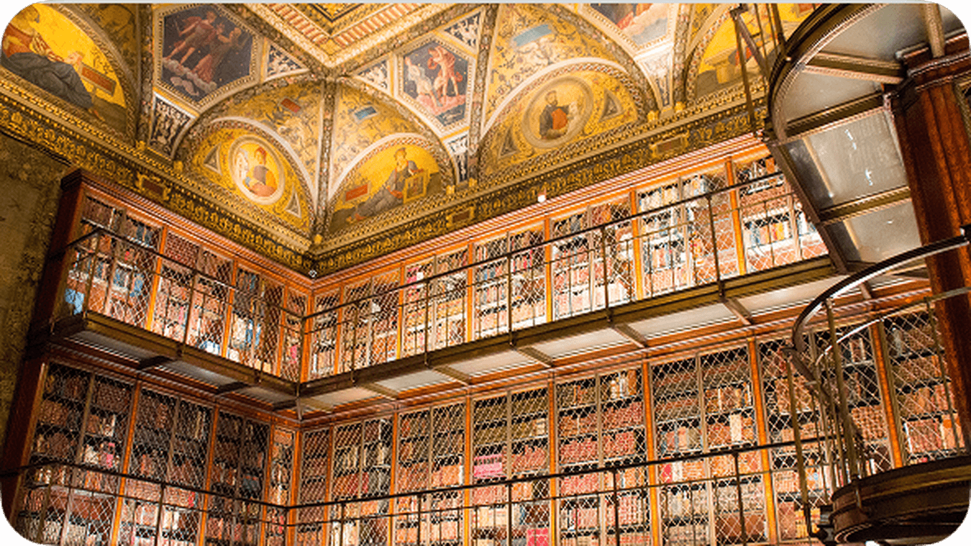 Ornate library interior with decorative ceiling, wooden bookshelves filled with books, and a metal spiral staircase.