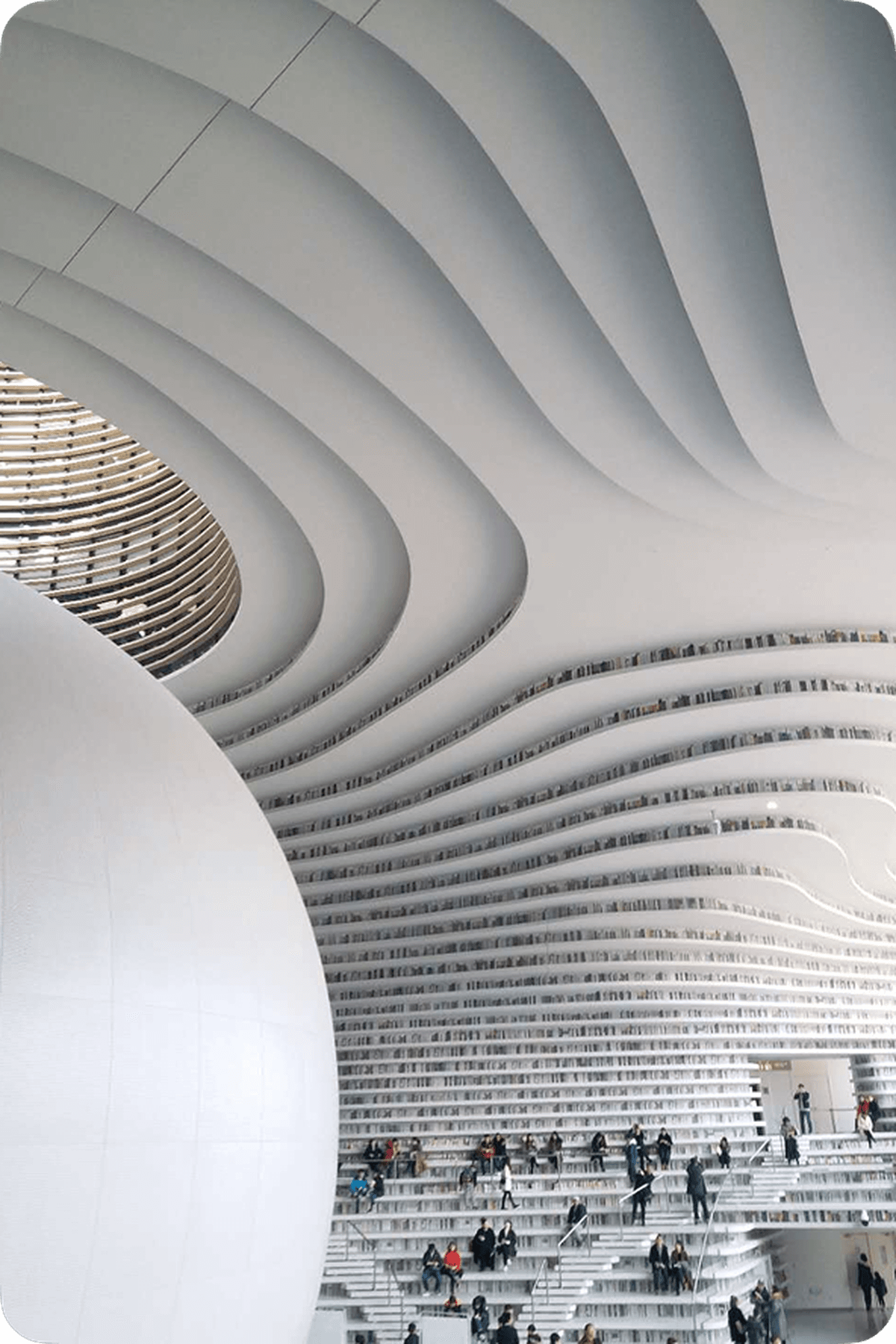 Futuristic library interior with wave-like ceiling, spherical structure, and tiered bookshelves. People explore the space.