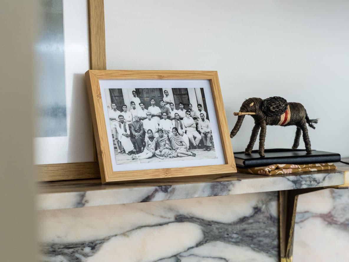 A framed black and white photo showing people in Rajasthan sits on a marble mantelpiece