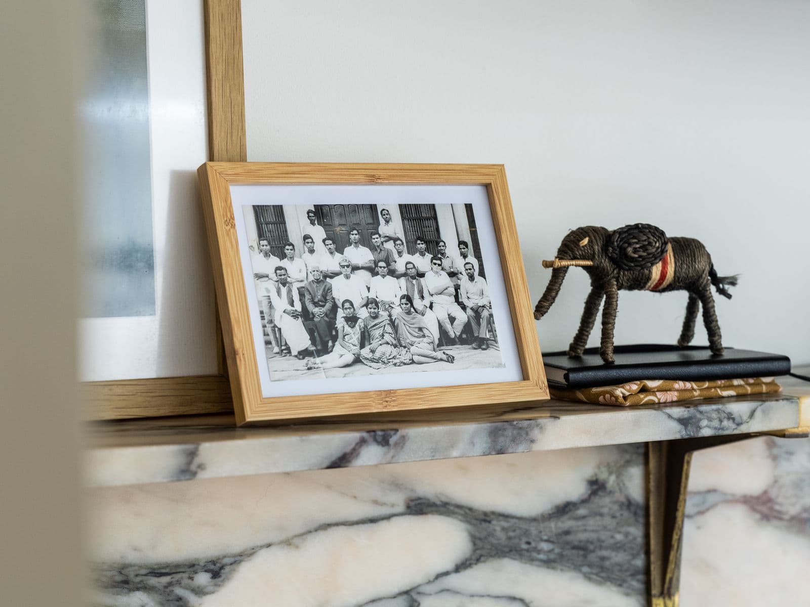 A framed black and white photo showing people in Rajasthan sits on a marble mantelpiece