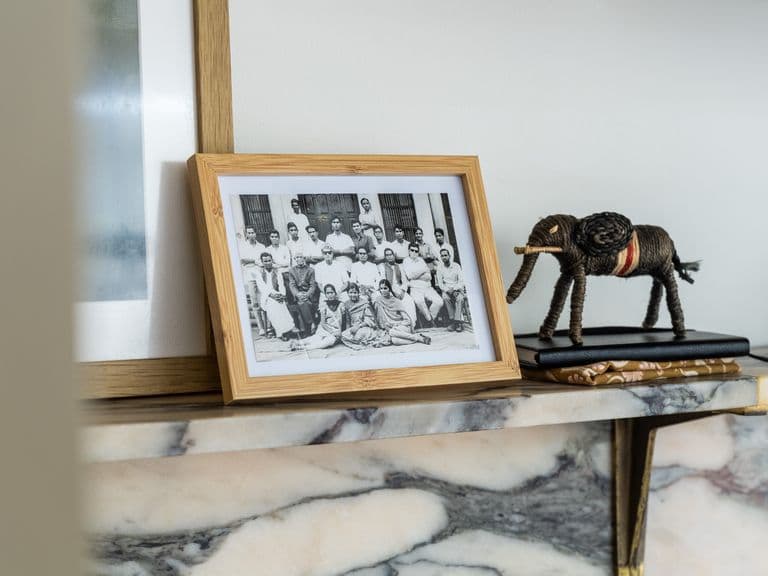 A framed black and white photo showing people in Rajasthan sits on a marble mantelpiece