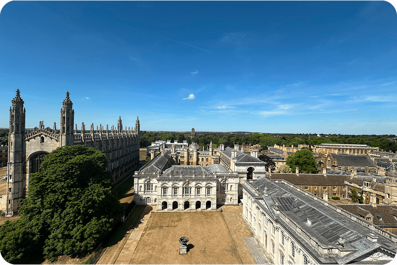 Aerial view of a historic university campus with Gothic architecture, green lawns, and clear blue sky in the background.