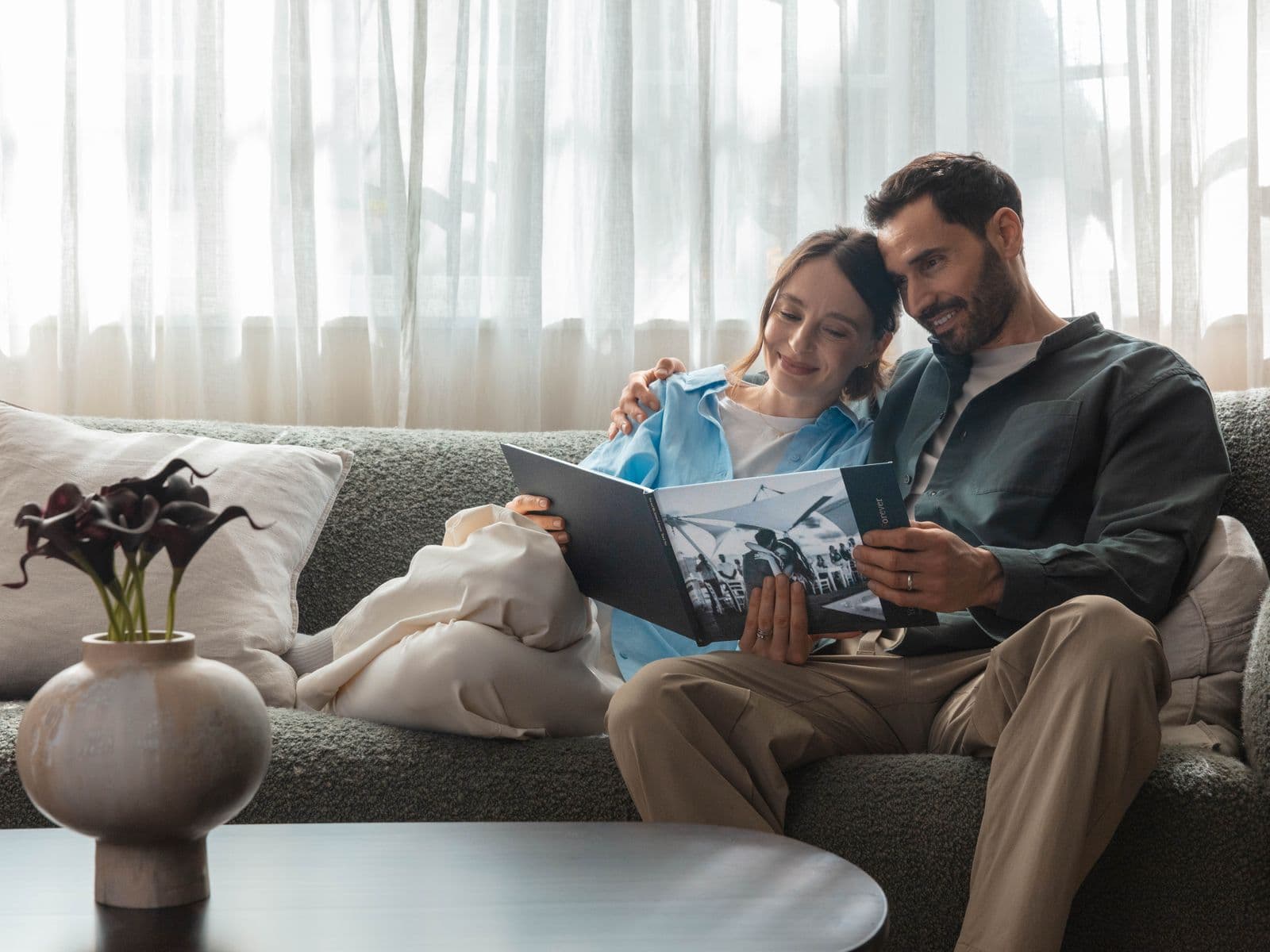Newlyweds sit on a sofa looking through their wedding photo book