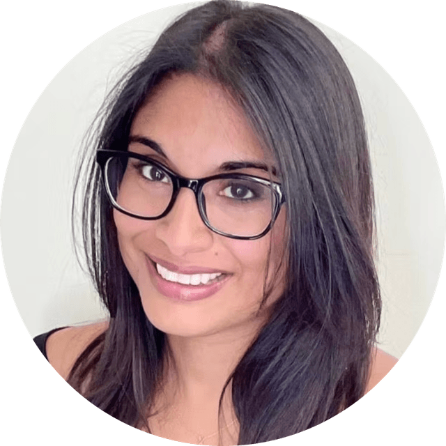 Close-up portrait of a smiling woman with long dark hair and black glasses against a light background.