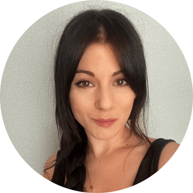 Woman with long dark hair in a braid, wearing a black top, smiling slightly against a neutral background.