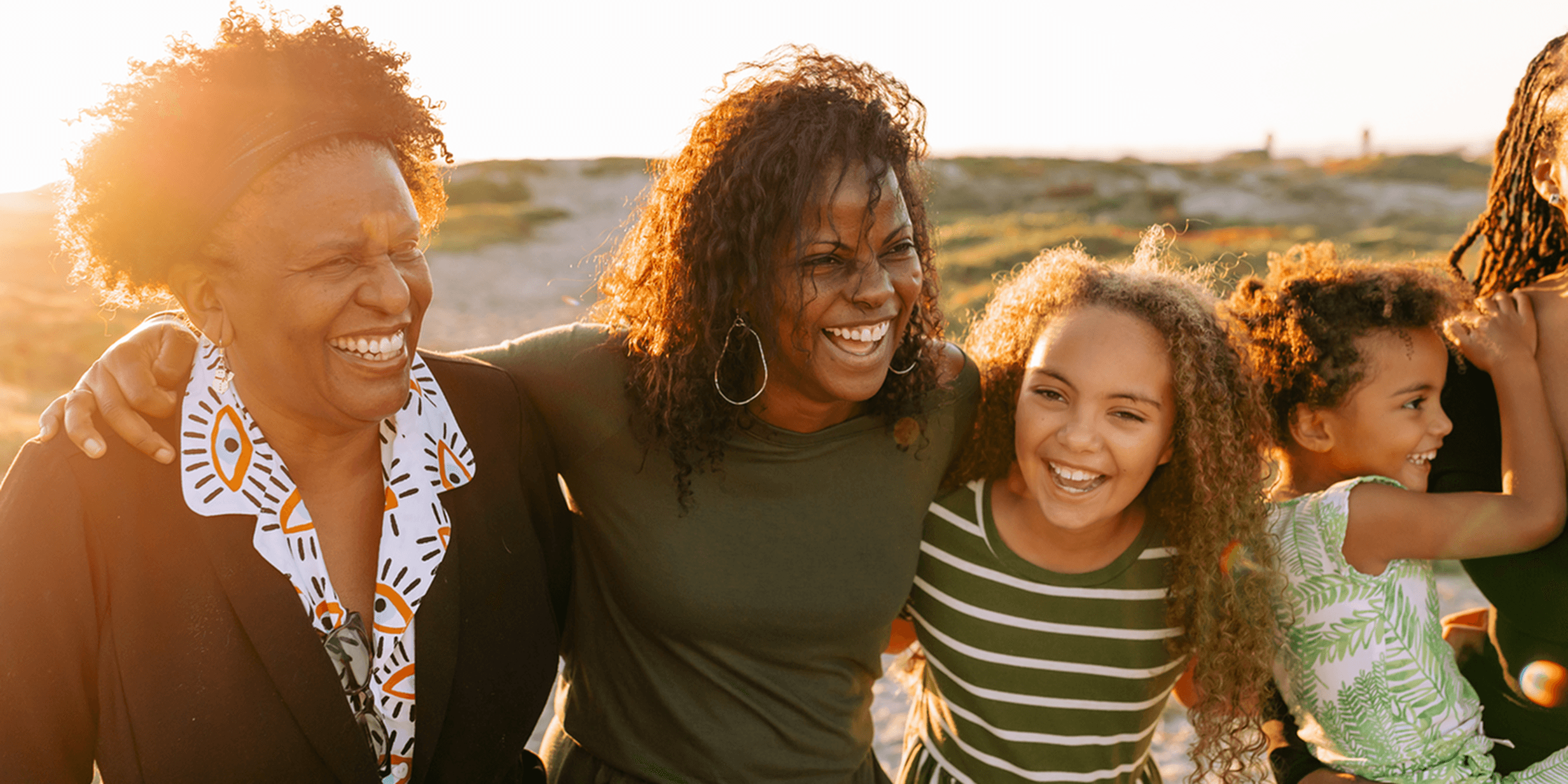 A mother, daughter and grandma smiling and hugging in a park setting
