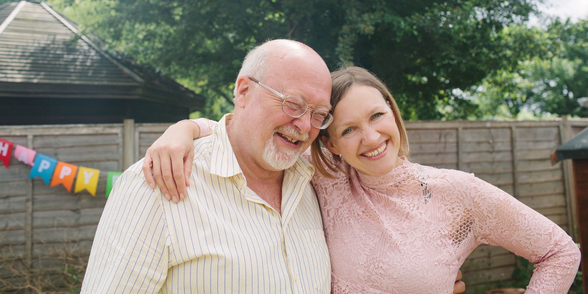 Father and daughter cuddling at outdoor birthday party