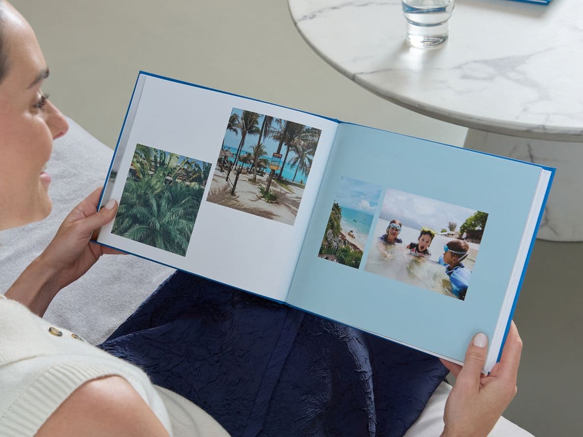 A woman holds a Popsa Photo Book with a blue cover