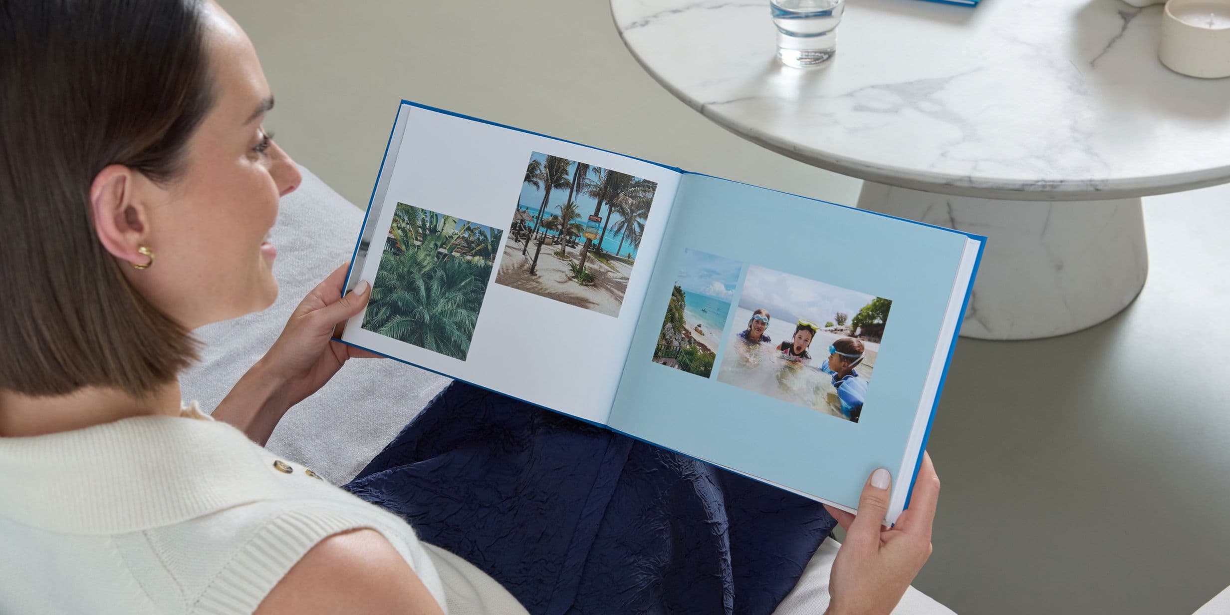 A woman holds a Popsa Photo Book with a blue cover