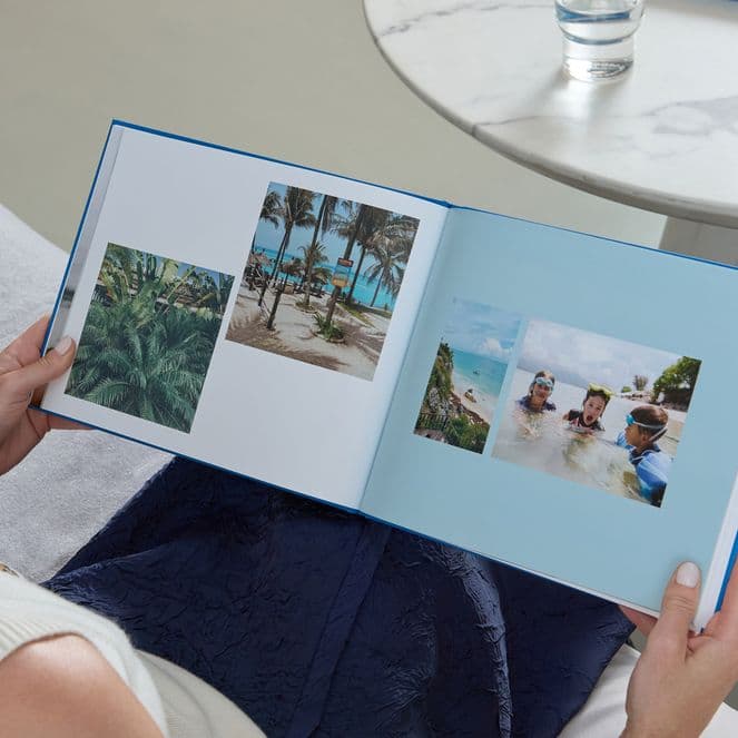 A woman holds a Popsa Photo Book with a blue cover