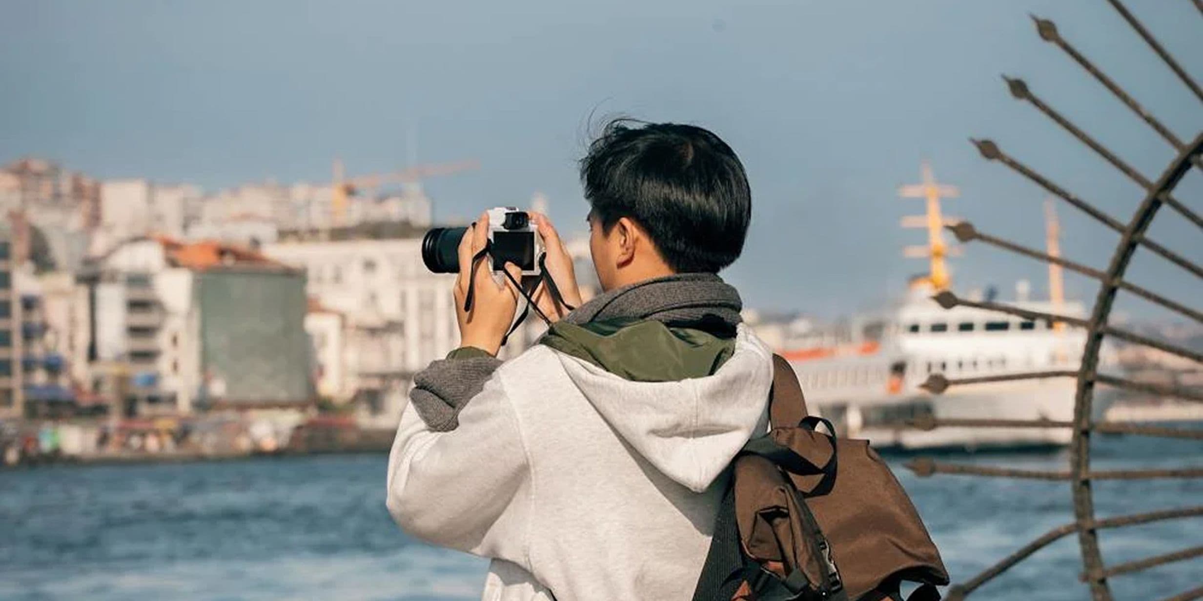 A tourist taking photos of a city across a body of water