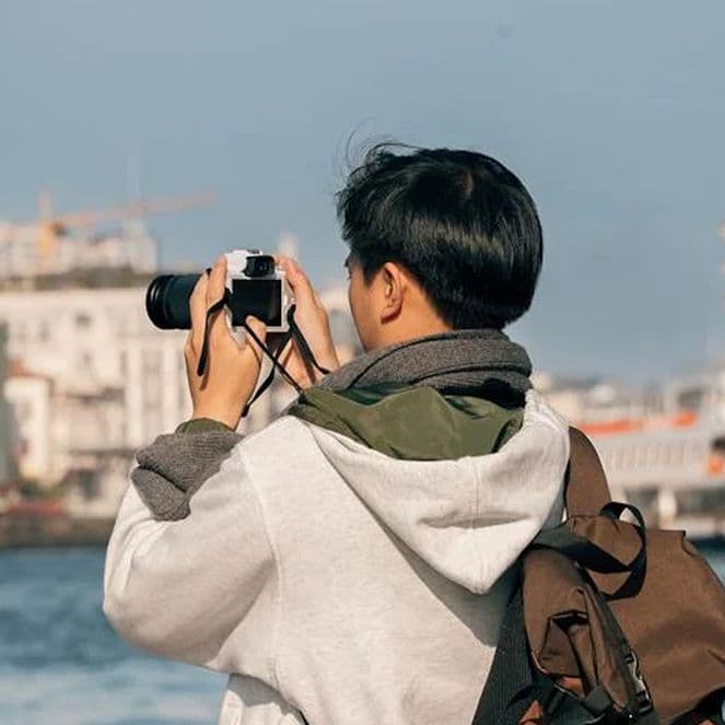 A tourist taking photos of a city across a body of water