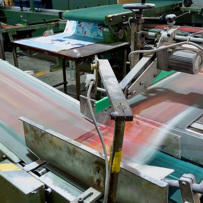 A factory conveyor belt system in motion, transporting printed materials through various machinery in an industrial setting.