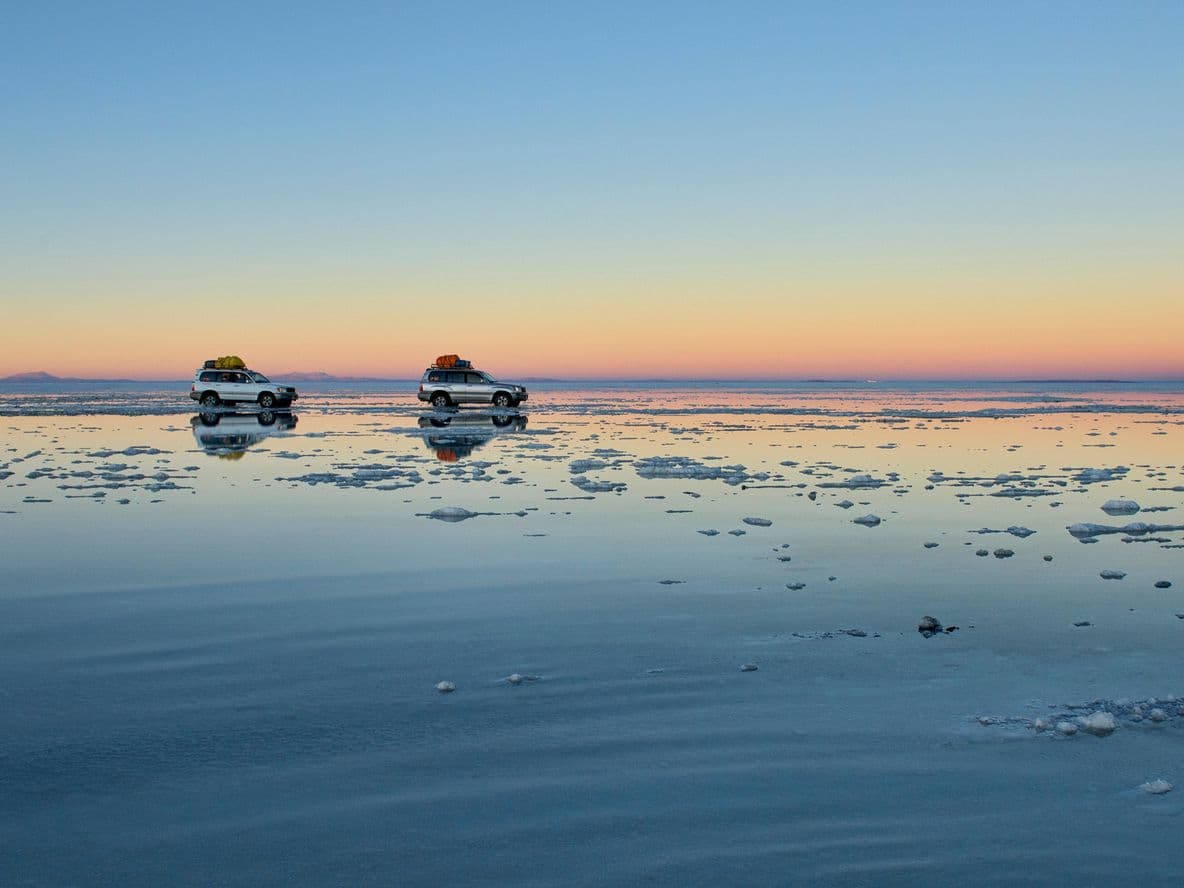 Two touring cars drive across salt flats, Uyuni, Bolivia