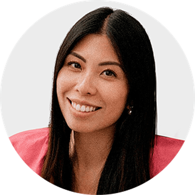 Smiling woman with long dark hair, wearing a pink top, against a plain background.