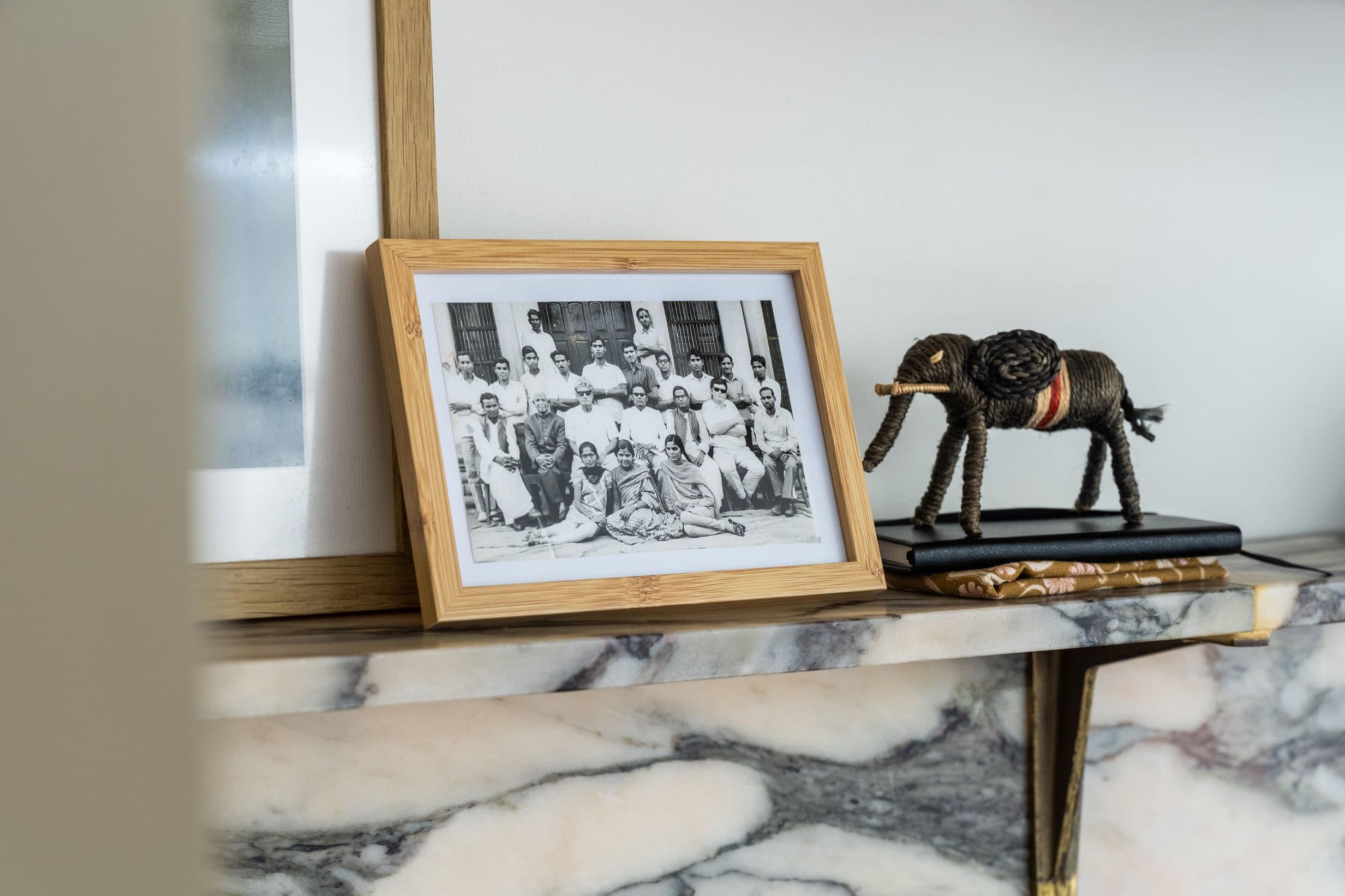 A framed black and white photo showing people in Rajasthan sits on a marble mantelpiece