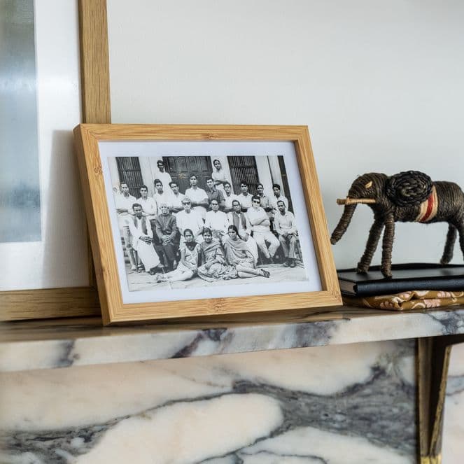 A framed black and white photo showing people in Rajasthan sits on a marble mantelpiece