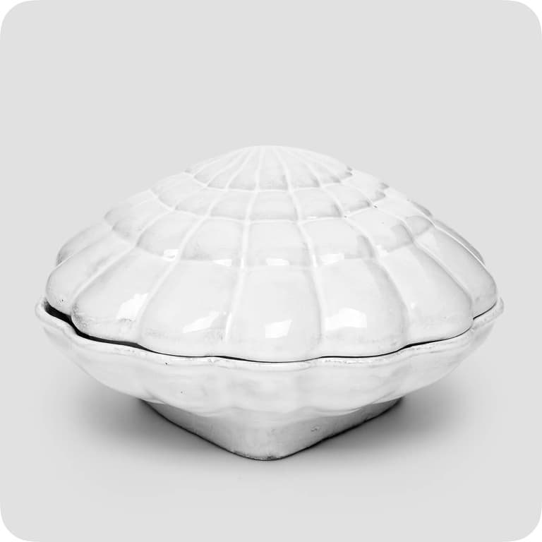 White ceramic shell-shaped container with a ridged lid, set against a plain gray background.