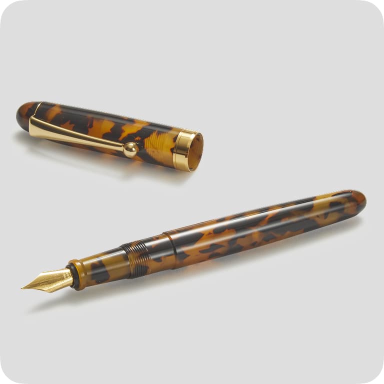 Tortoiseshell-patterned fountain pen with a gold nib and cap, featuring gold accents, displayed on a light gray background.