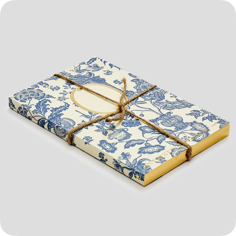 Decorative book set with blue floral patterns, tied with twine, on a light gray background.
