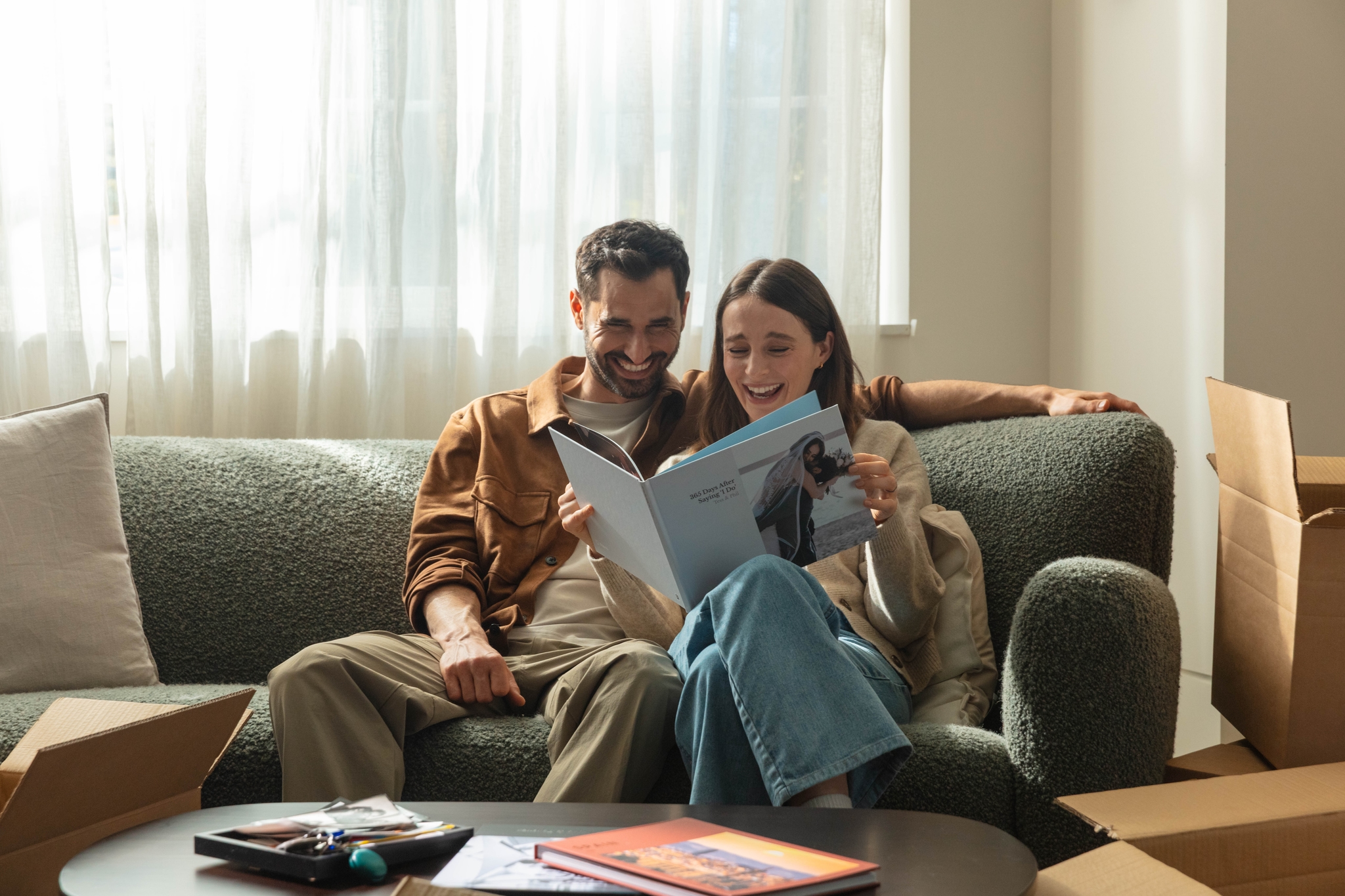 A married couple looking back at their wedding photos in an anniversary photo book on a sofa